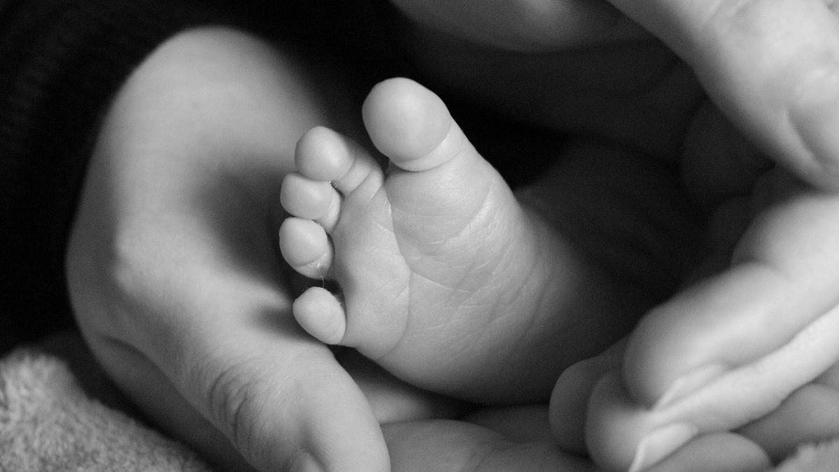Bebeğini kucağında tutan anne ve masadaki kahve fincanı