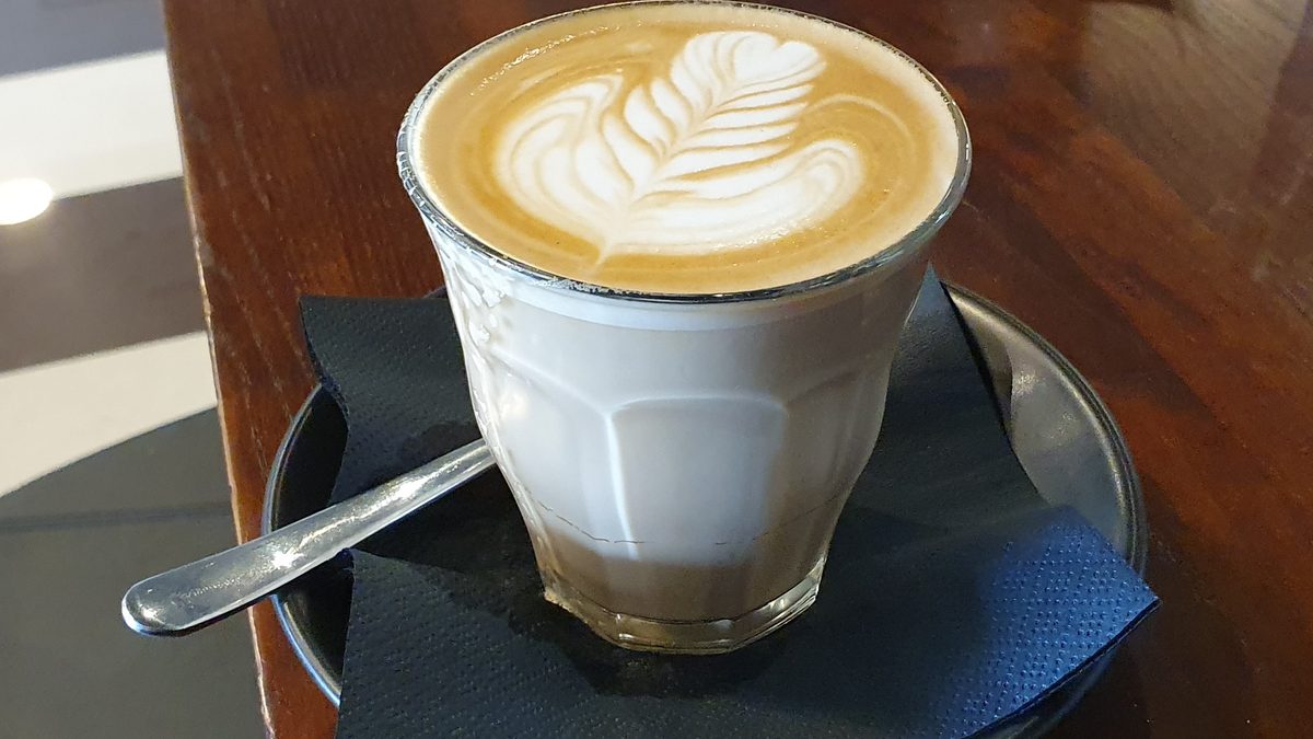 İnce köpüklü ve latte artlı bir bardak latte